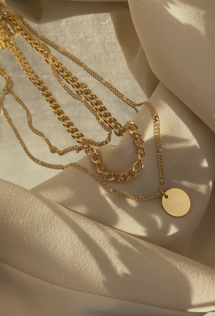 Gold chains laying on a beige cloth surface